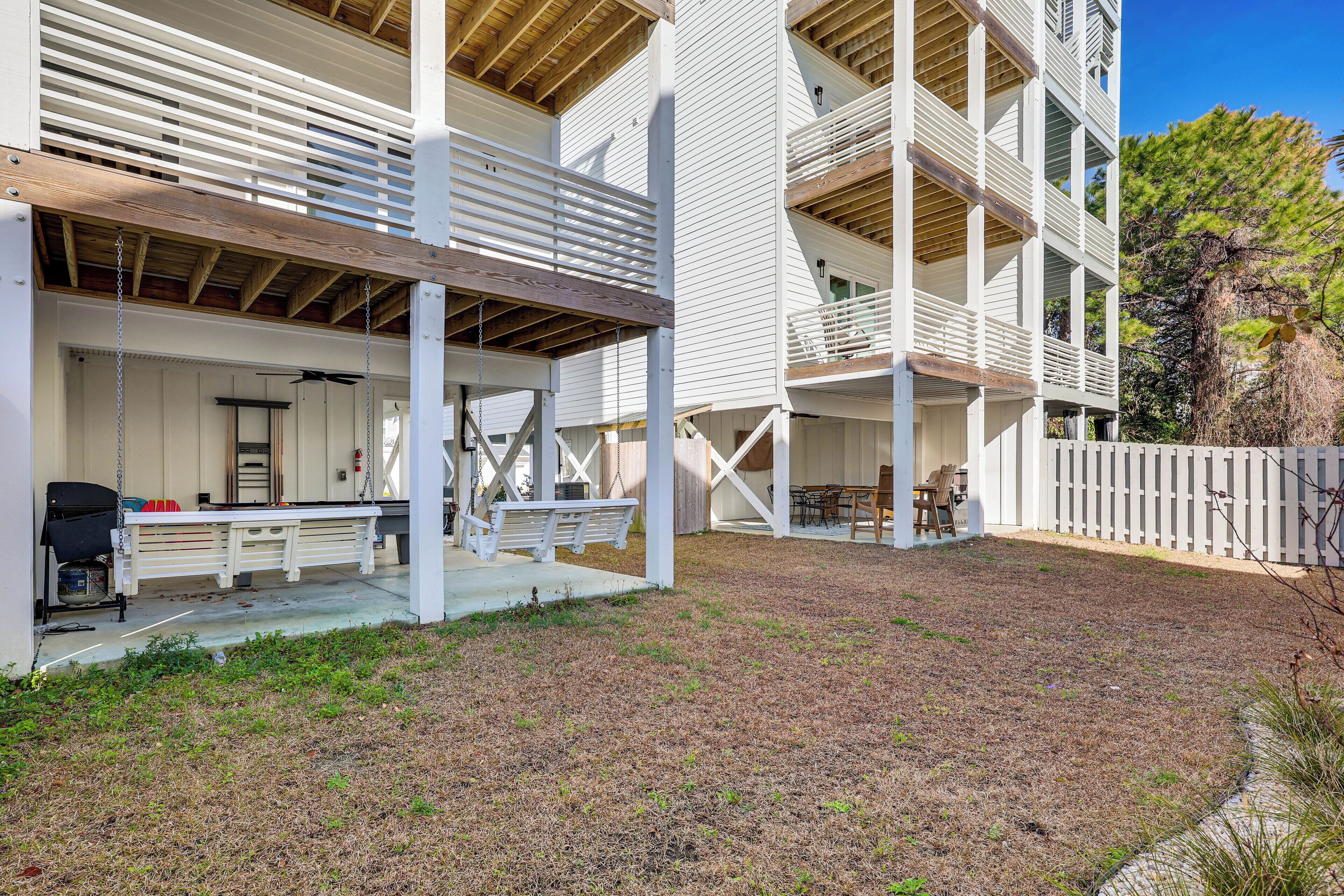 A multi-story building with a covered patio area, outdoor seating, and a fenced yard.