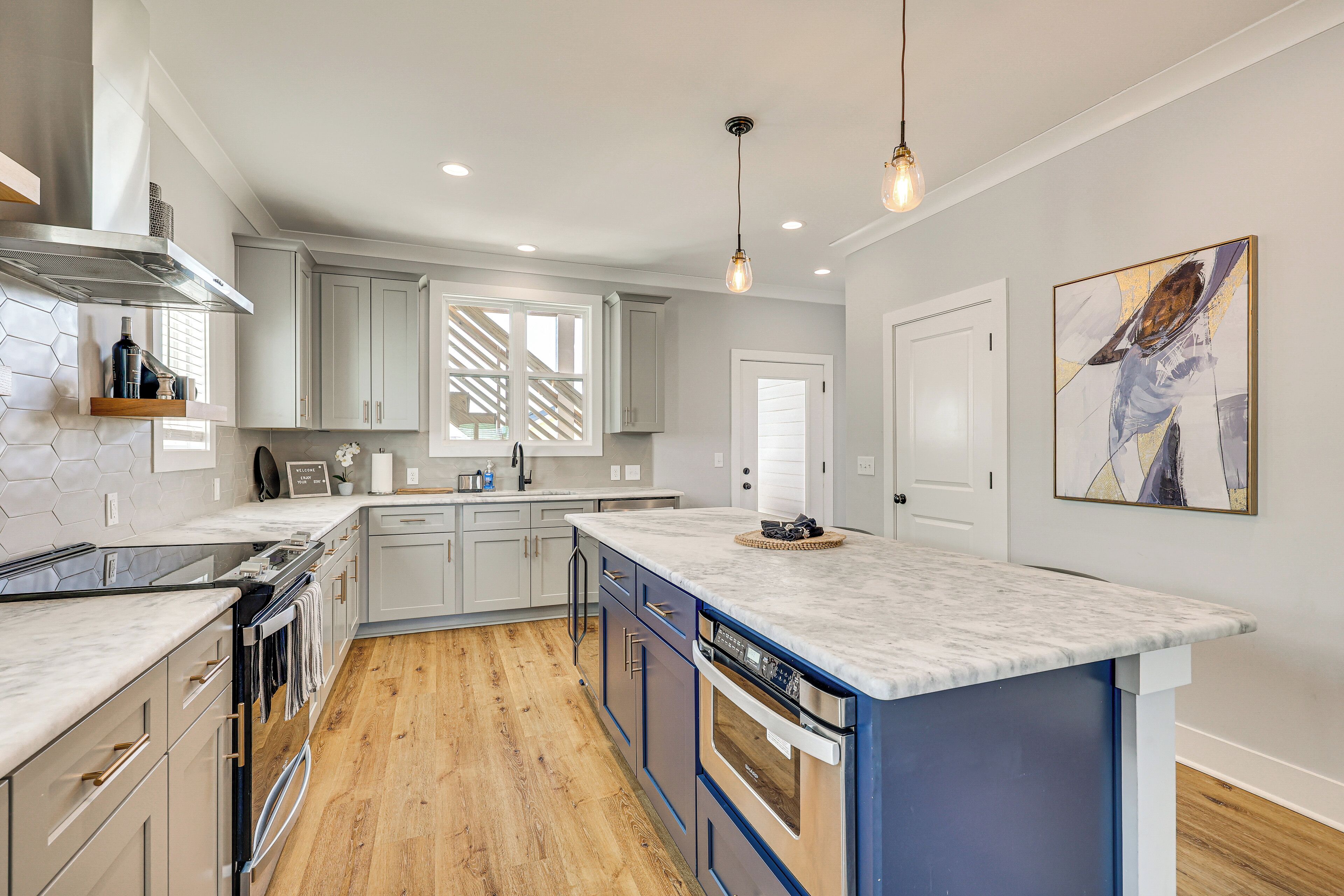 A modern kitchen with a large island, built-in appliances, and a wooden floor.