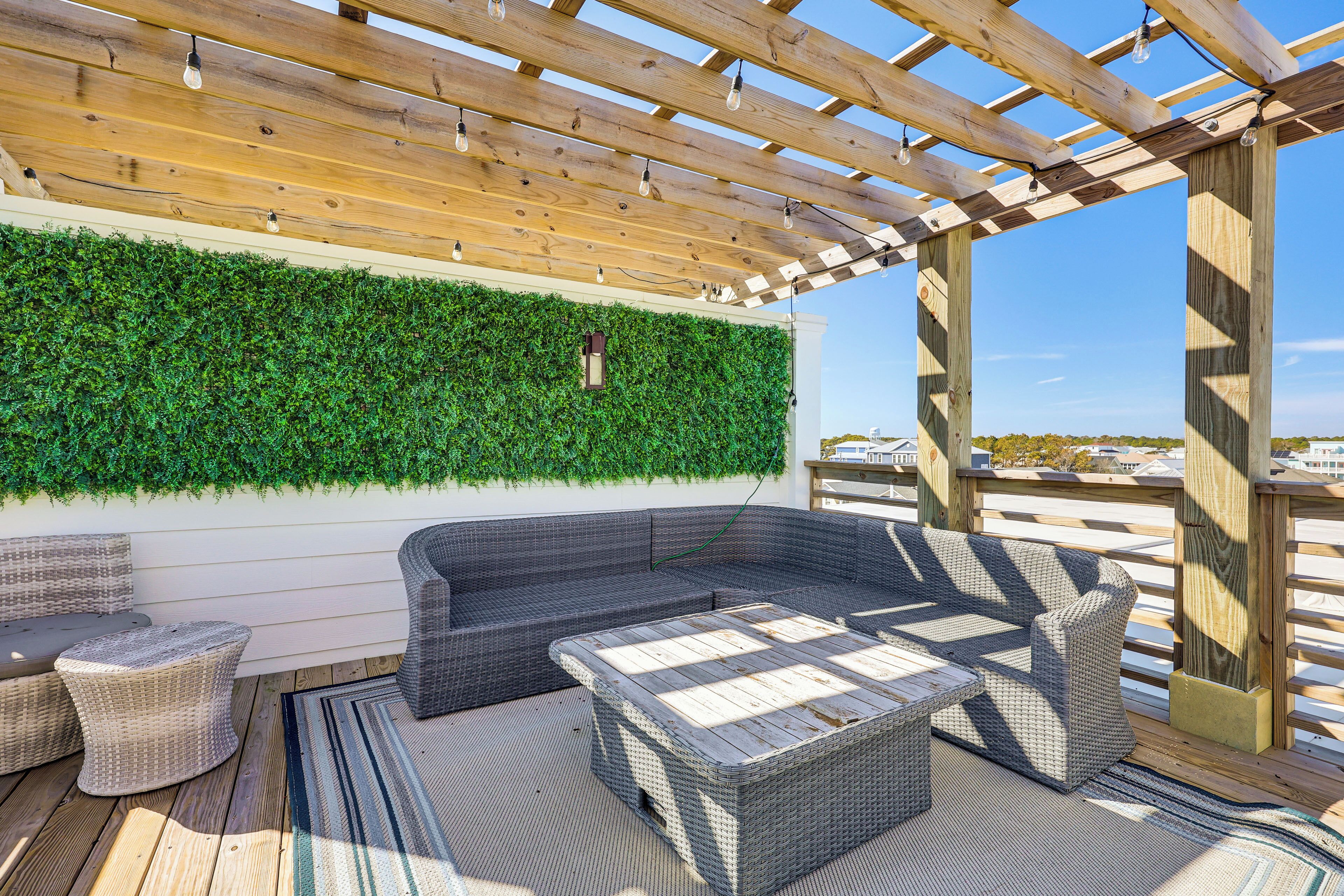 A covered outdoor seating area with a green wall and wooden ceiling.