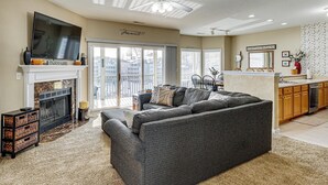 Een woonkamer met een open haard, een grote grijze modulaire bank en een televisie op een schoorsteenmantel.