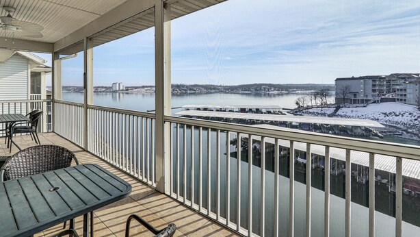 Een overdekt balkon met uitzicht op een rivier en gebouwen aan de overkant.