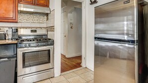 A kitchen with wooden cabinets, a stainless steel stove, and a refrigerator. - 2 Mi to UBS Arena & Belmont Park: Suburban Escape (Elmont)