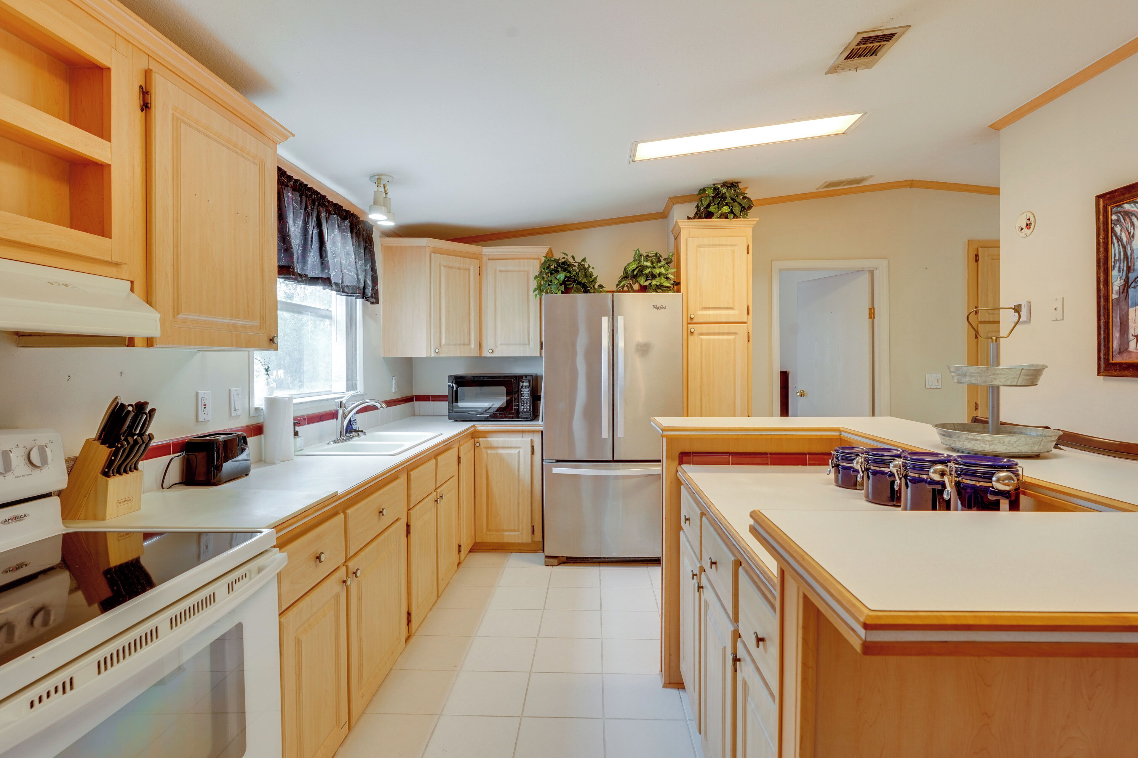 A kitchen with wooden cabinets, a stainless steel refrigerator, a microwave, and a stove.