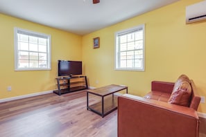 A living room with yellow walls, a brown leather sofa, a wooden coffee table, and a television on a stand. - Close to Downtown Ashland! Convenient Suite (Ashland)