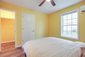 A bedroom with a bed, a ceiling fan, a window with blinds, a door, and a closet with hanging clothes. - Close to Downtown Ashland! Convenient Suite (Ashland)