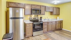 Una cocina con armarios de madera, electrodomésticos de acero inoxidable y un ventilador de techo.