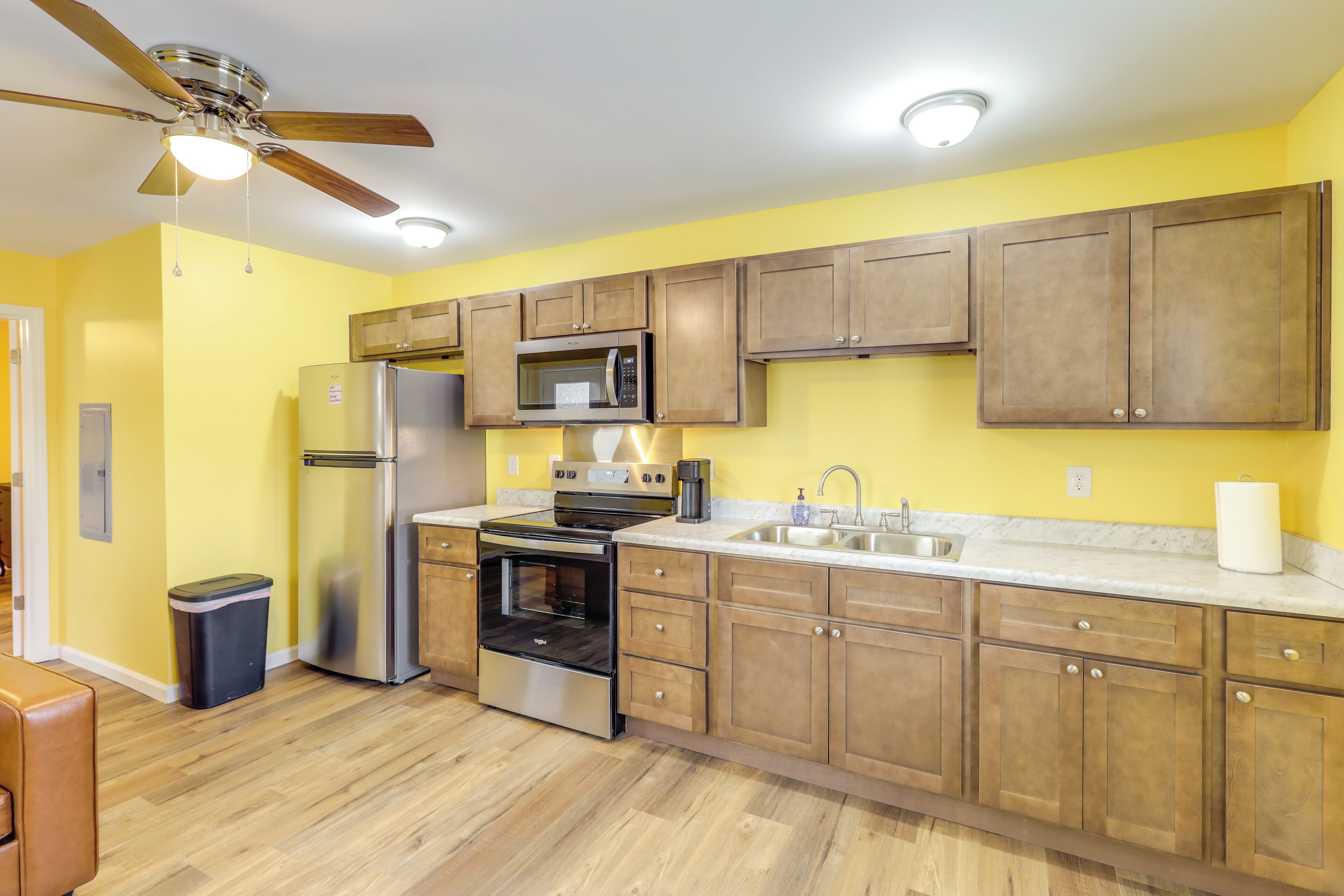 A kitchen with wooden cabinets, stainless steel appliances, and a ceiling fan.