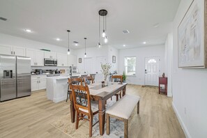 A modern kitchen with white cabinets, stainless steel appliances, and a wooden dining table with chairs. - 6 Mi to Trails! Tranquil Home w/ Yard in Ocala (Ocala)