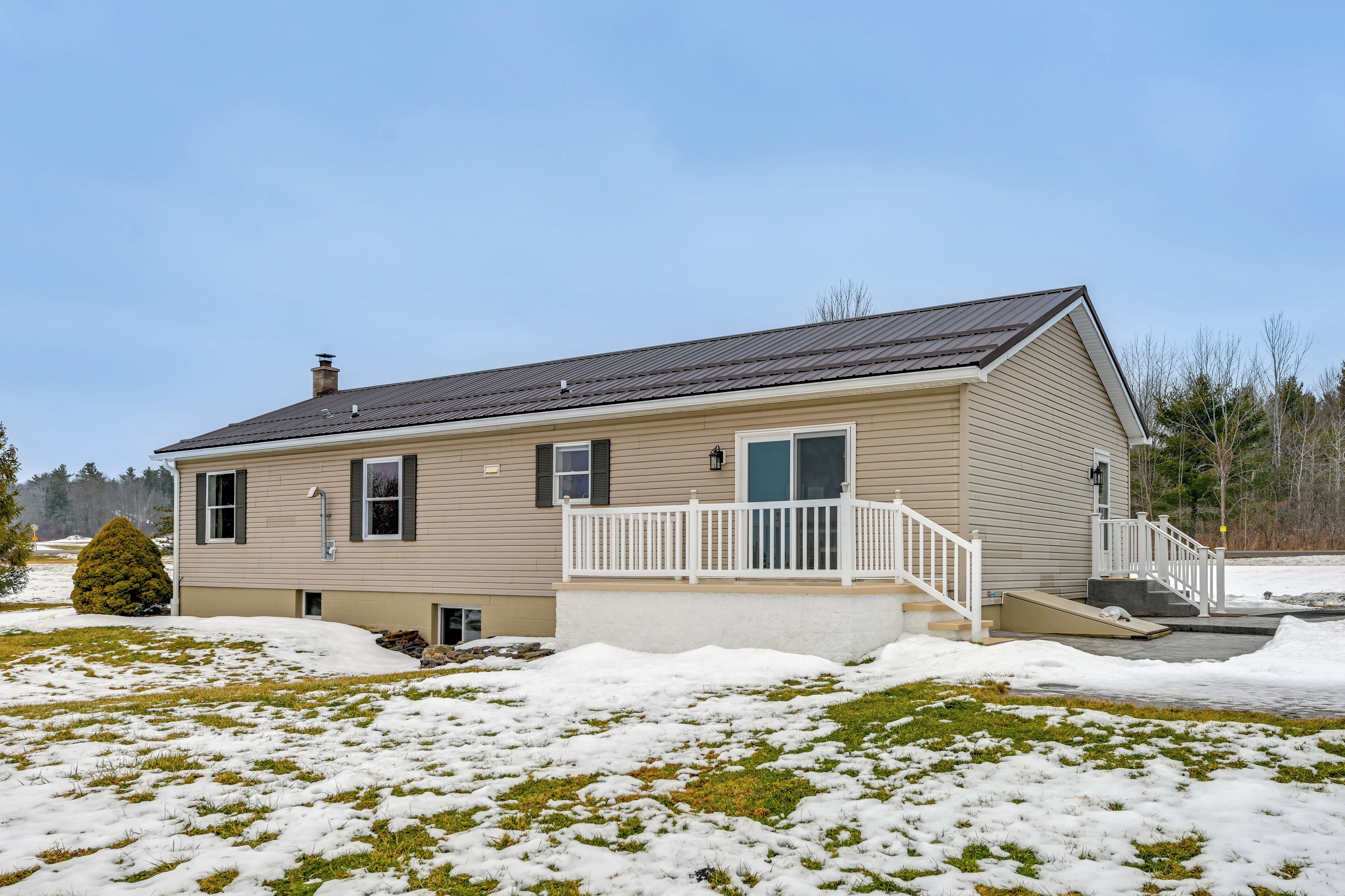 A single-story house with a front porch, a small front yard, and a snow-covered lawn.