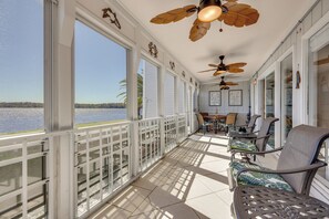 A covered outdoor area with a view of the water, furnished with chairs and tables, and ceiling fans. - Boat, Fish & Swim: Condo on St Johns River! (Welaka)