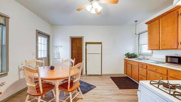 Una cocina con armarios de madera, un refrigerador blanco, un microondas y una mesa de comedor con sillas.