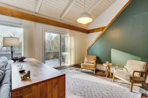 A cozy living room with a wooden coffee table, two chairs, a sofa, and a large window. - Resort-style Community! Quechee Chalet w/ Deck (Quechee)