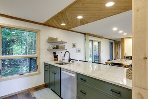 A kitchen with a large window, wooden ceiling, and a dishwasher. - Resort-style Community! Quechee Chalet w/ Deck (Quechee)