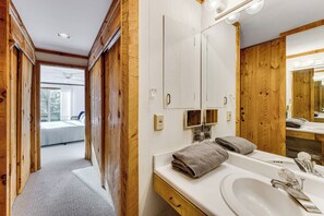 A bathroom with wooden paneling, a large mirror, and a sink with towels. - Resort-style Community! Quechee Chalet w/ Deck (Quechee)