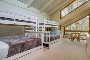 A room with bunk beds, a dining table with chairs, and large windows. - Resort-style Community! Quechee Chalet w/ Deck (Quechee)