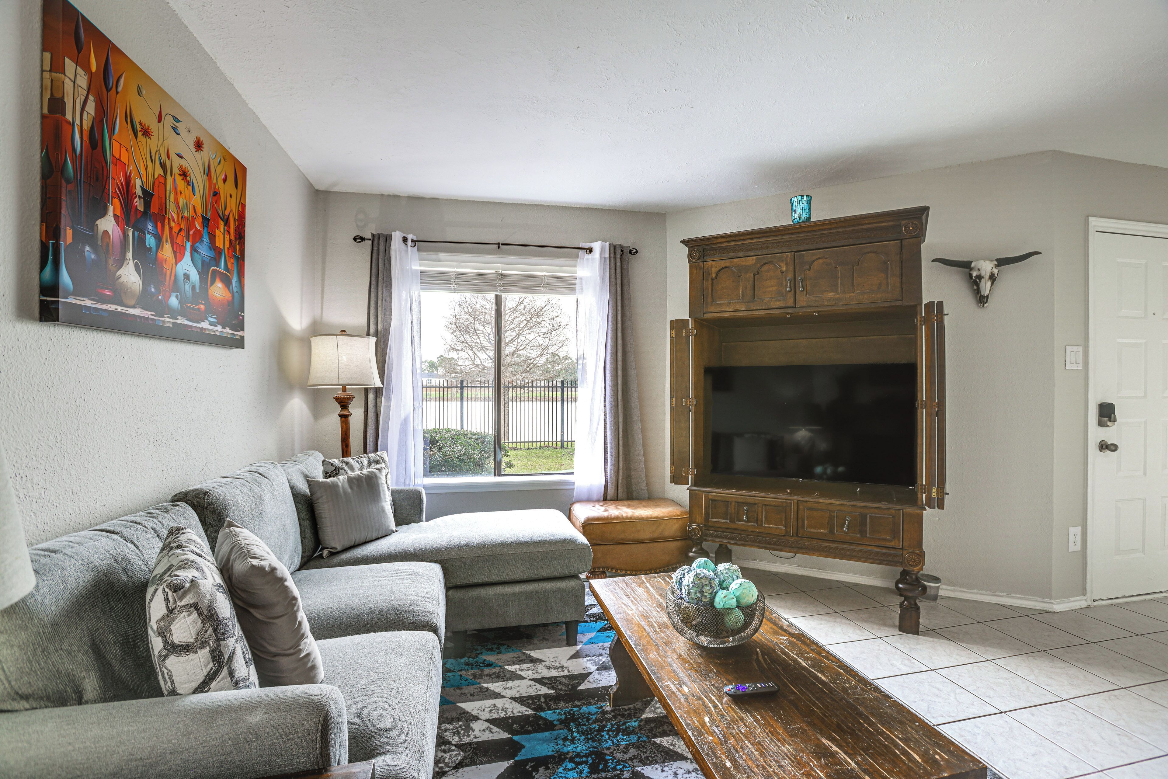A living room with a sofa, a coffee table with decorative items, a television, and a painting on the wall.