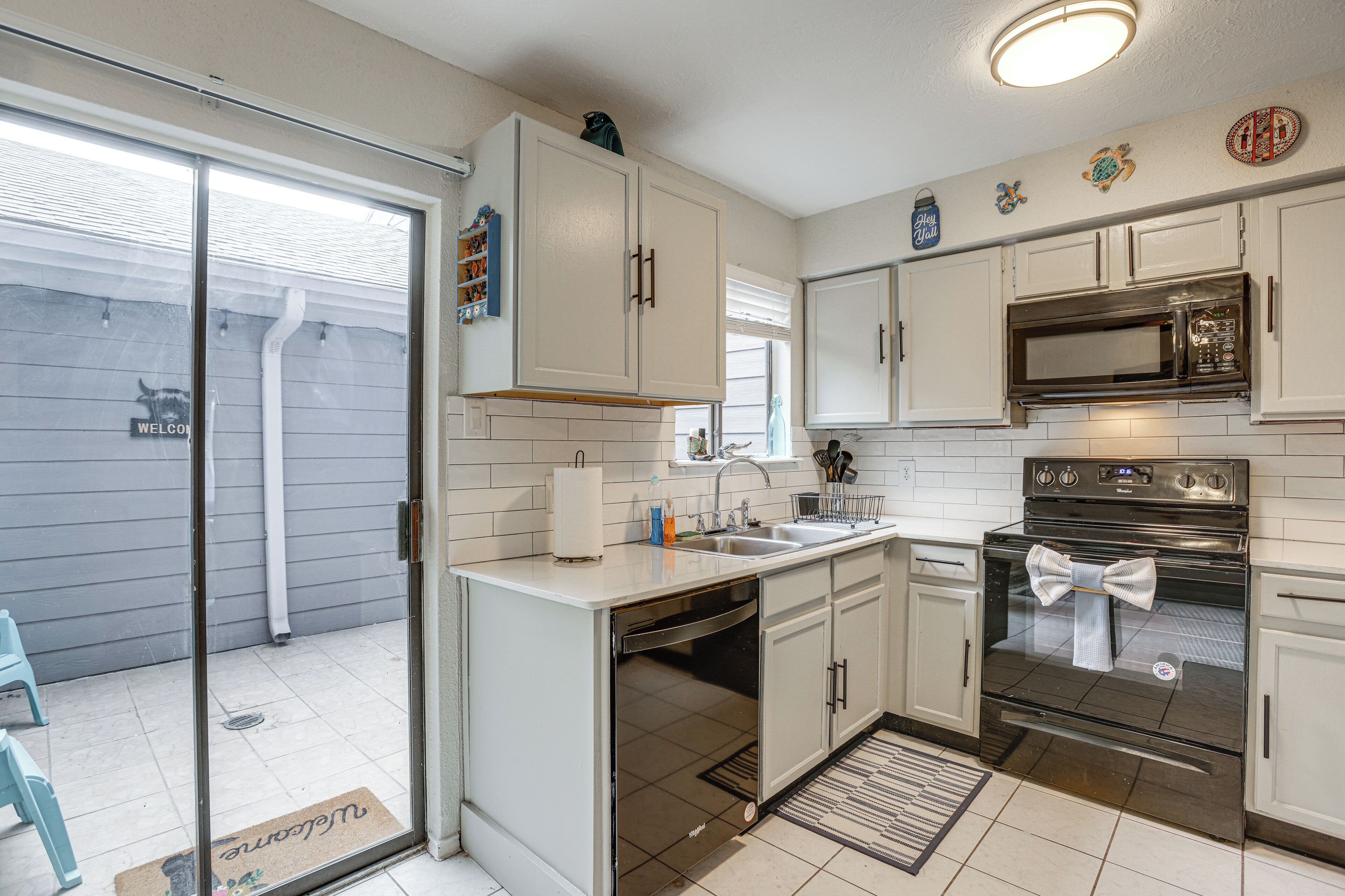 A kitchen with white cabinets, a stainless steel microwave, and an oven.