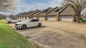 A row of townhouses with attached garages, a paved driveway, and a grassy area with trees. - Lake-view Townhome w/ Pool Access in Houston Area! (Missouri City)