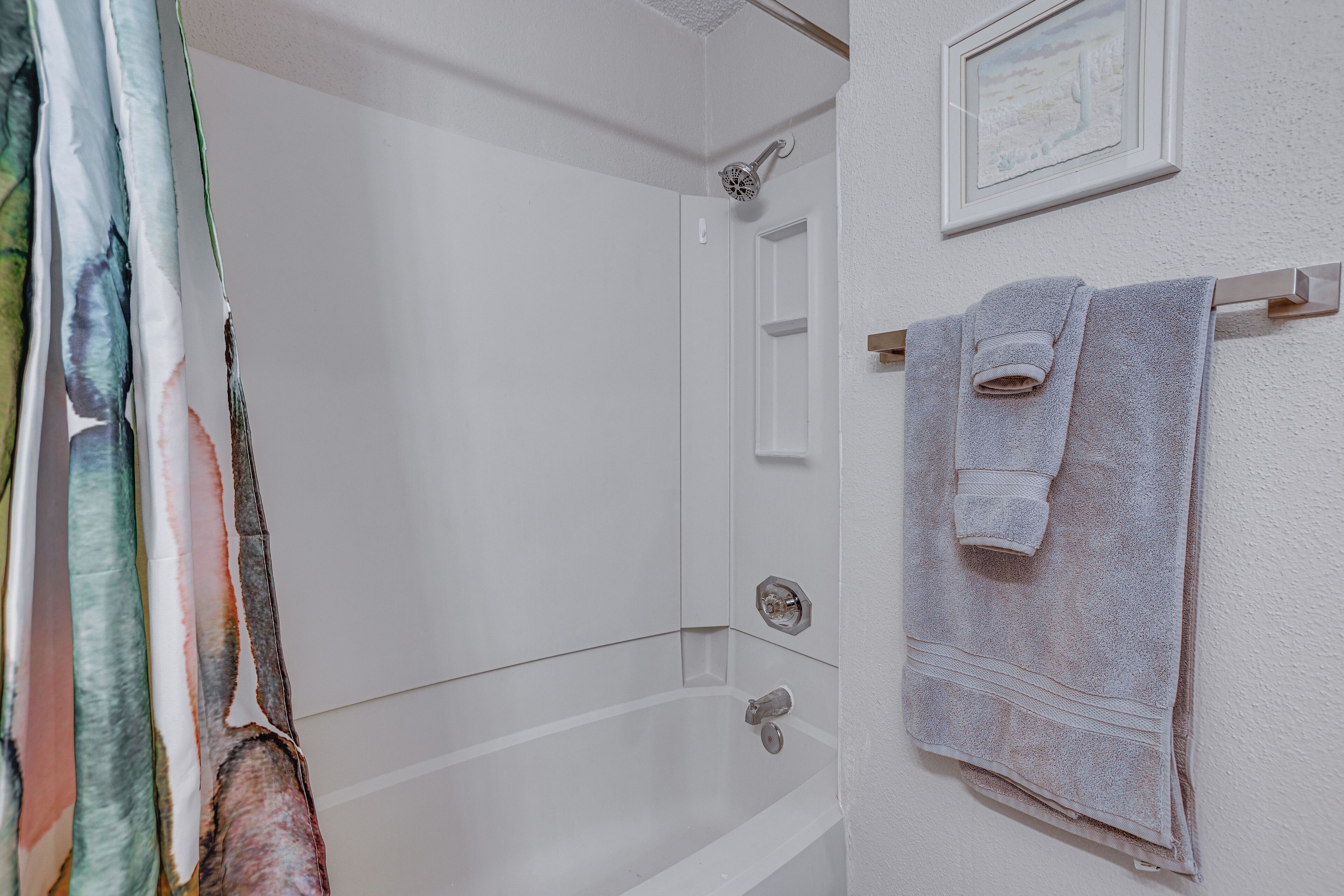 Ein Badezimmer mit einer Badewanne, einer Dusche und einem Handtuchhalter mit zwei Handtüchern.
