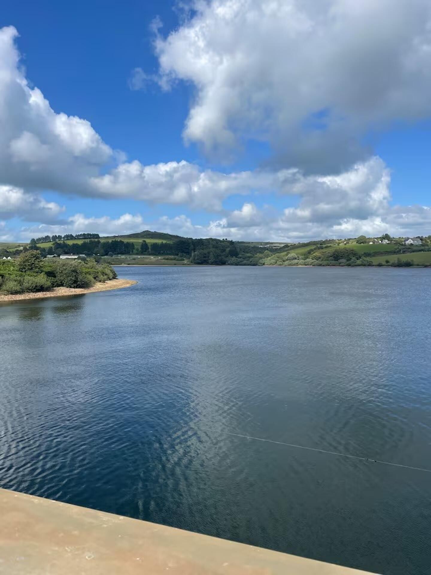 Un río tranquilo con cielo despejado y colinas distantes.