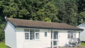 A small, single-story building with a tiled roof and a sign indicating it is a lodge. - 2 Bed Cottage - Sleeps 5 - Pets - Parking - Garden (Liskeard)