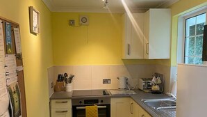 A compact kitchen with white cabinets, a stove, and a sink. - 2 Bed Cottage - Sleeps 5 - Pets - Parking - Garden (Liskeard)