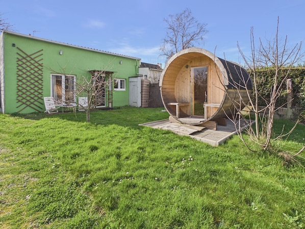 A green building with a wooden sauna structure in the yard.