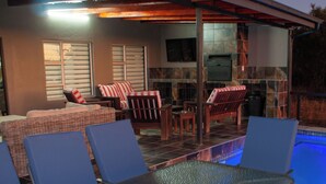 Un espace extérieur aménagé avec une terrasse, une piscine, des sièges et une cheminée en pierre.