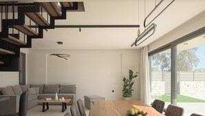 Een moderne woonkamer met een houten eettafel, een grijze bank en een trap.