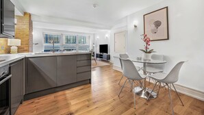Una cucina moderna con mobili grigi, un'isola in legno e un'area pranzo con tavolo in vetro e sedie in metallo.