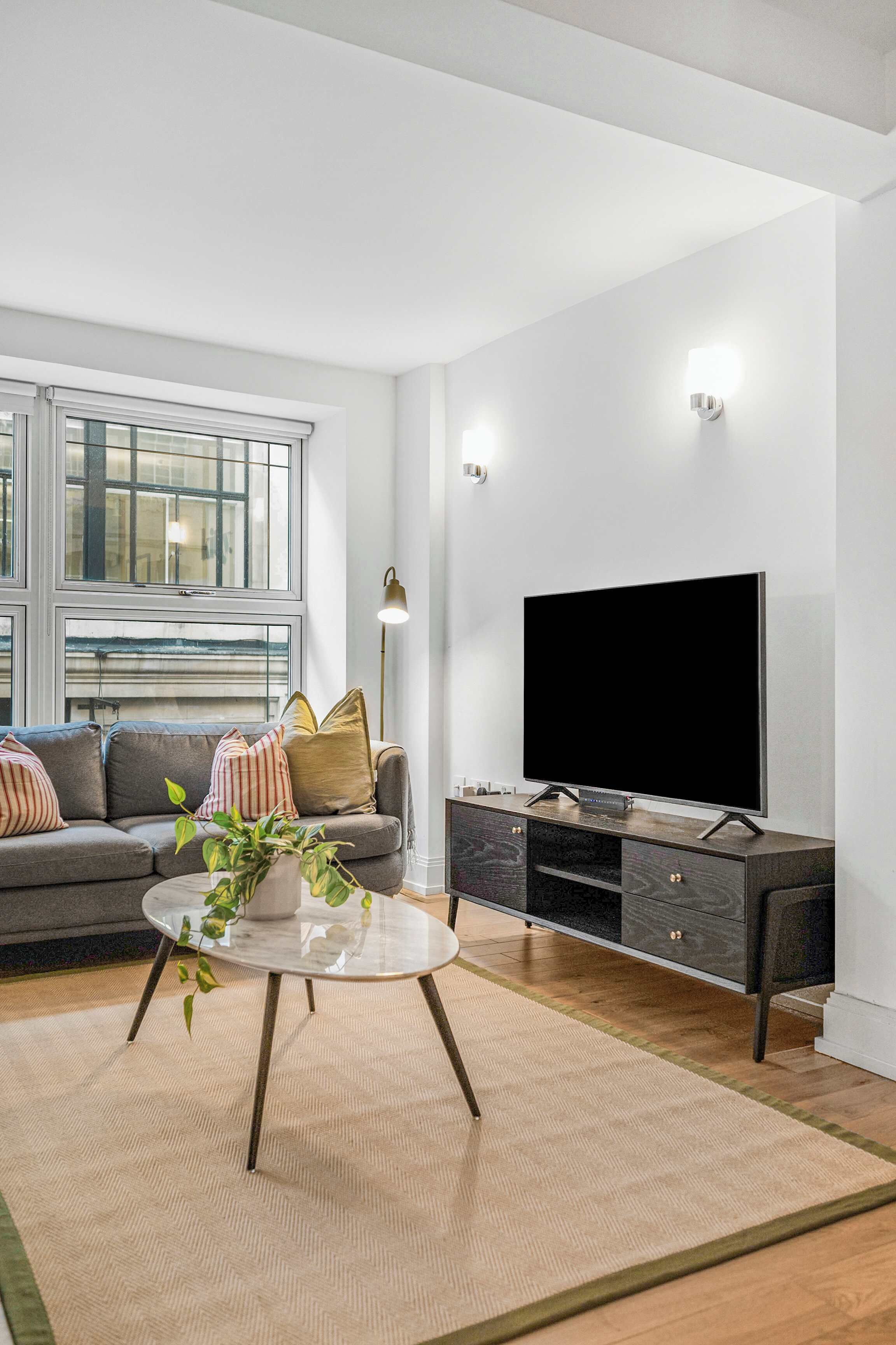 A modern living room with a sofa, a coffee table, a flat-screen TV, and a sideboard.