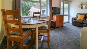 Un coin repas avec une table ronde, des chaises en bois et un téléviseur posé sur un meuble.