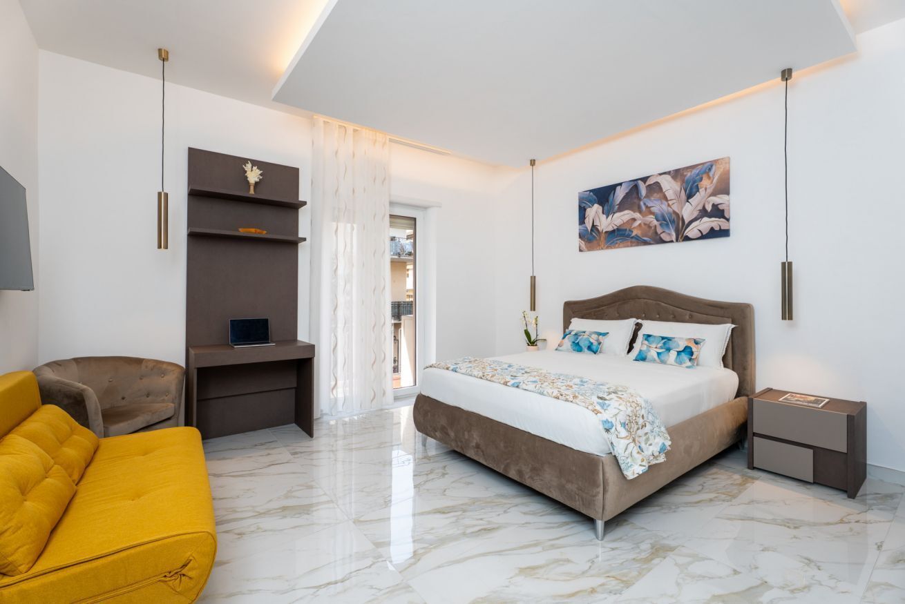 Een moderne slaapkamer met een bed, een slaapbank, een bureau en een schilderij aan de muur.