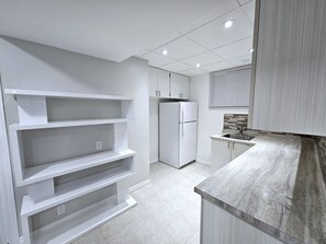 Eine moderne Küche mit weißen Schränken, einem eingebauten Kühlschrank und einer Marmorarbeitsplatte.