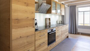 A modern kitchen with wooden cabinets, a built-in oven, and a large window with curtains. - 5* vacation home 188sqm with high-quality comfort with 4 bedrooms and space for 7 people (Sankt Andreasberg)