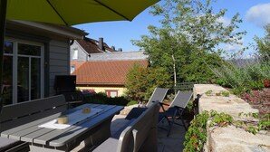 An outdoor patio with a table and chairs, a grill, and a yellow umbrella. - 5* vacation home 188sqm with high-quality comfort with 4 bedrooms and space for 7 people (Sankt Andreasberg)