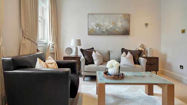 Una sala de estar con sofá, sillón, mesa de centro y elementos decorativos.