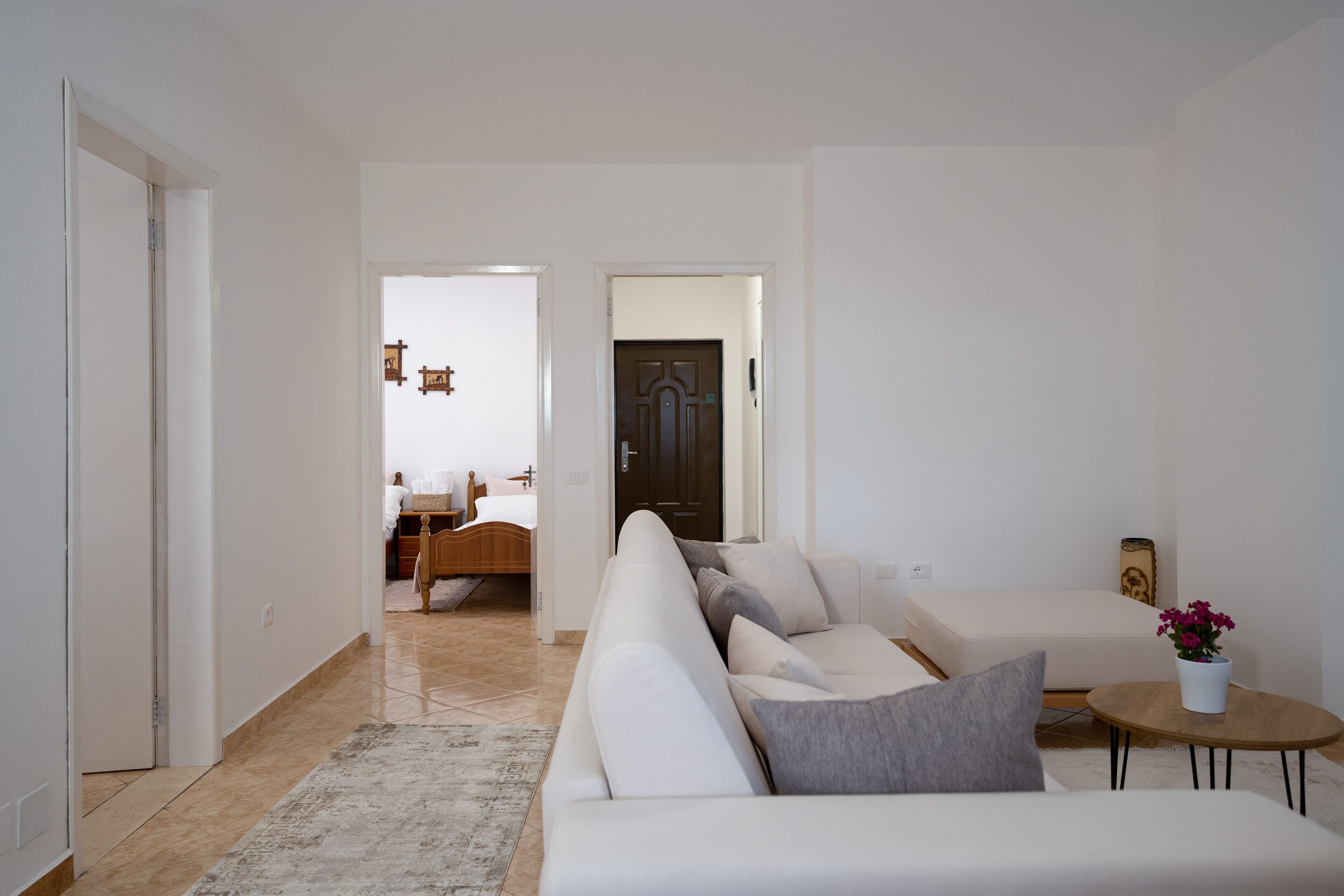 A modern living room with a sofa, a coffee table, and a small side table with a flower vase.