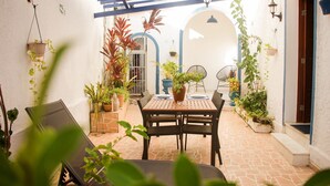 A patio with a table and chairs, potted plants, and a blue ceiling. - Pousada Maria Maria (Salvador)