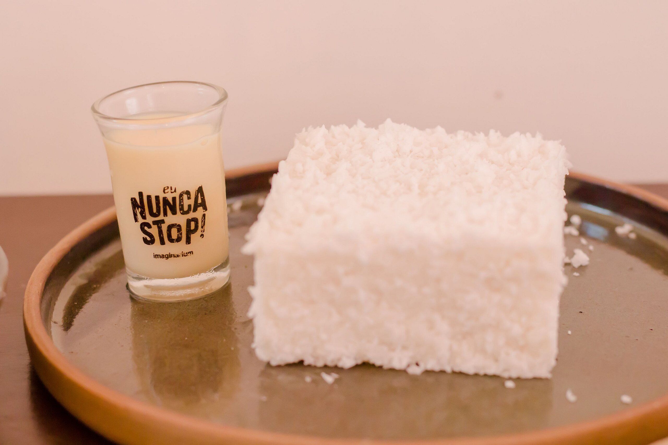 A glass with 'NUNCA STOP' text and a white cube on a plate.