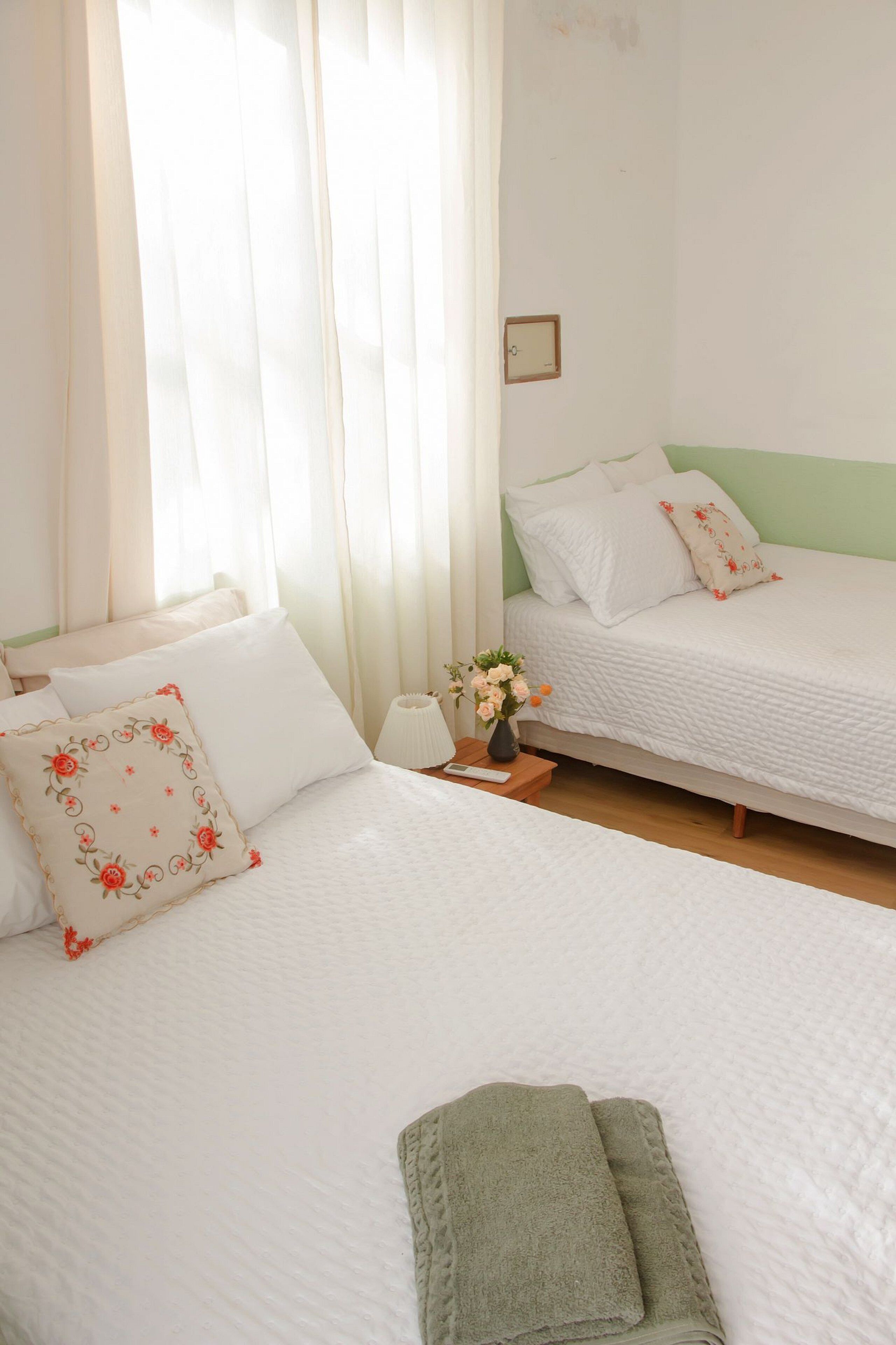 Une chambre d’hôtel avec deux lits, une table de chevet avec une lampe et un petit vase avec des fleurs.