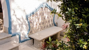 A bench with a floral pattern, a white wall with blue trim, and steps leading up to it. - Pousada Maria Maria (Salvador)