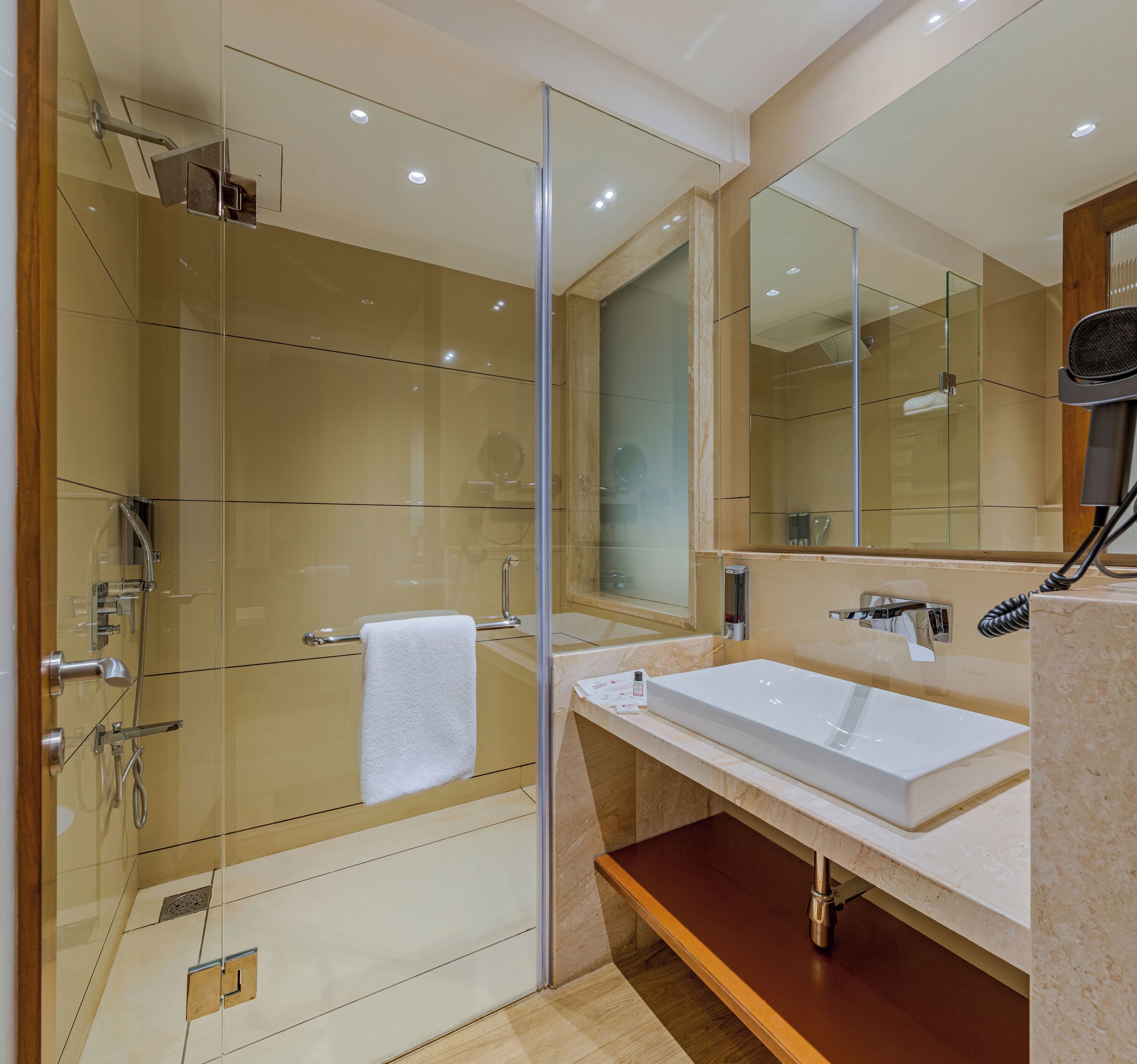 Un bagno moderno con cabina doccia in vetro, un lavandino bianco e uno specchio grande.