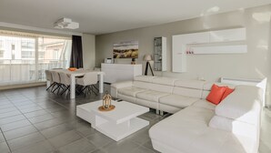 A modern living room with a white sofa, a dining table, and a white coffee table. - Duinenveld 2A 0801 met garage (Nieuwpoort)