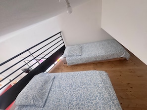 Une petite pièce, de taille modeste, comprenant un lit superposé et un lit simple, tous deux dotés de draps à motifs.