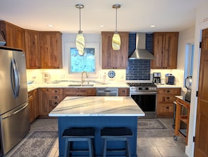 A modern kitchen with wooden cabinets, a marble island, stainless steel appliances, and pendant lighting. - NEW!  Eagles Landing - Large and Luxurious Newly-Constructed Lakefront Home Right On Crystal Lake!  Absolutely Gorgeous! (Beulah)