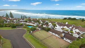 Zona residencial costera con casas, una cancha de tenis y una piscina.