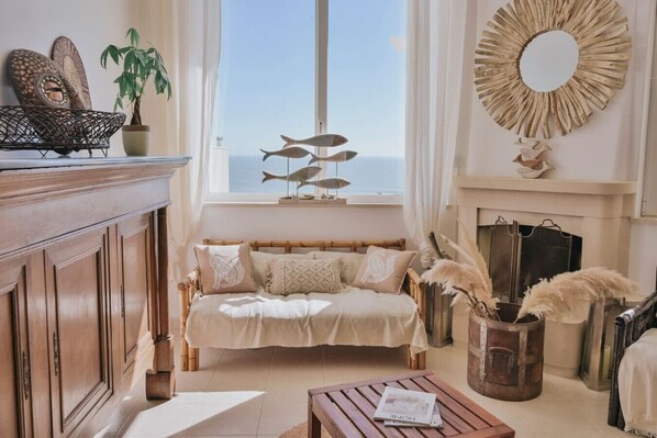 A cozy living room with a sofa, a fireplace, a window with a view, and decorative items.