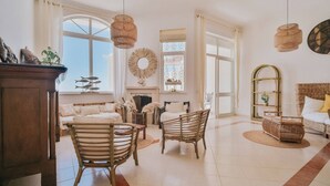 Un salon spacieux avec une grande fenêtre, des meubles en osier et une cheminée.