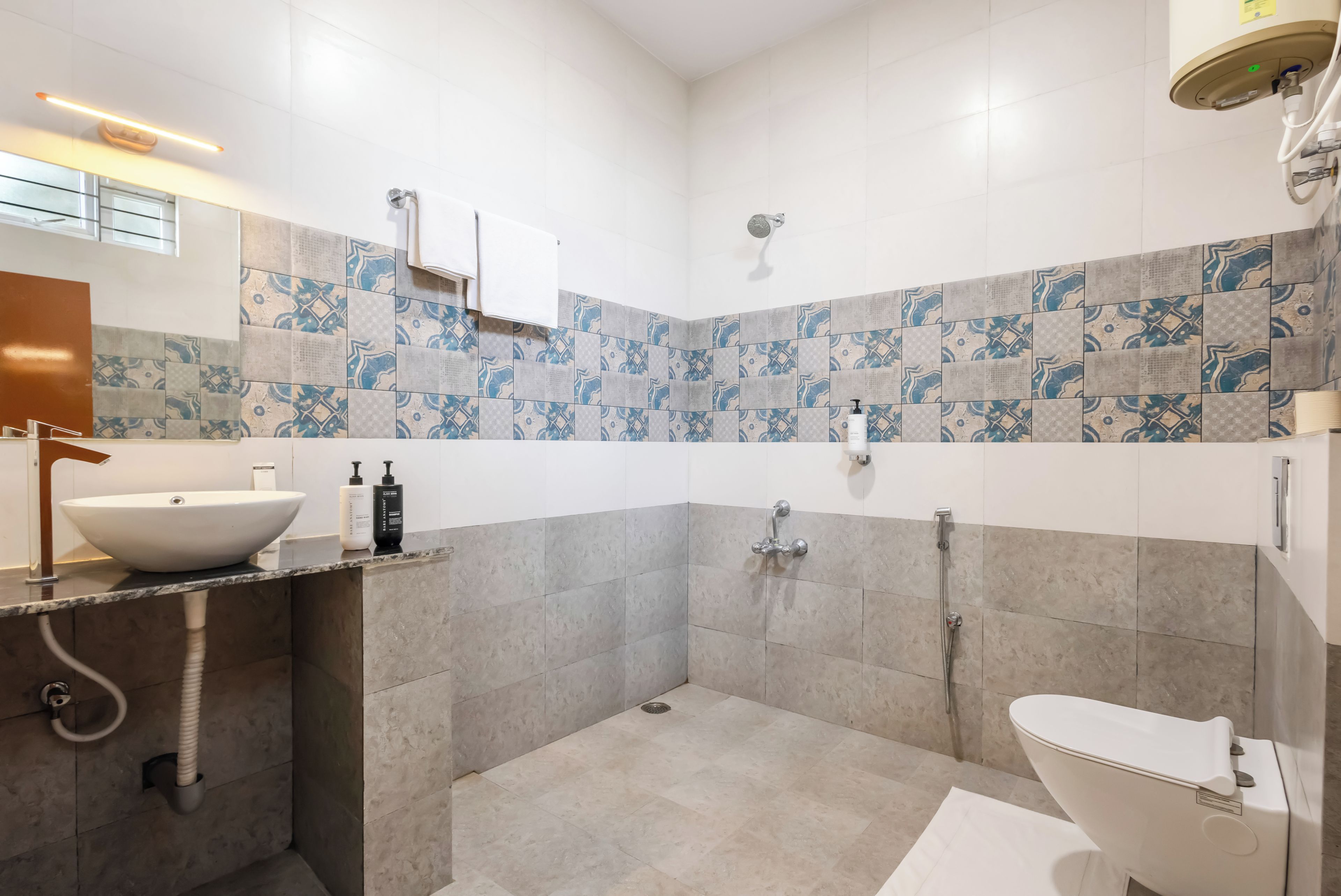 Un baño moderno con un lavamanos grande, un inodoro, una ducha y un espejo.